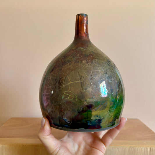 A porcelain raku-fired vase in iridescent hues of green, red and blue. Made by Hillit Wahlberg