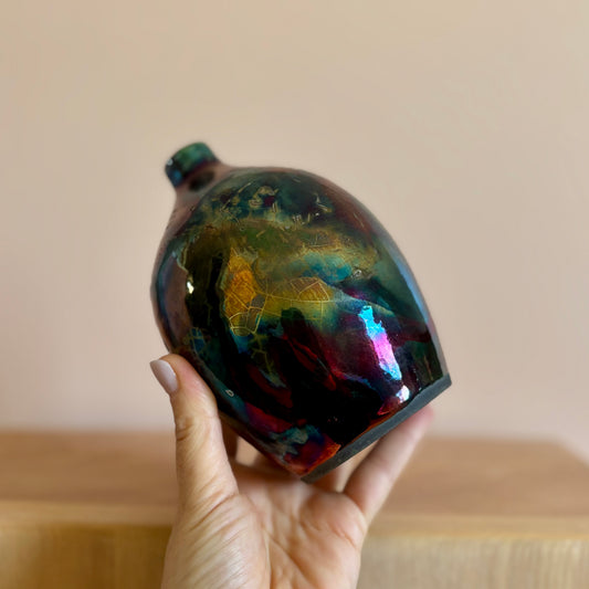 A small porcelain raku-fired vase in iridescent hues of green blue and purple with a crackle effect. Made by Hillit Wahlbeg