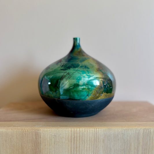 A round porcelain raku-fired vase in shaded of green
