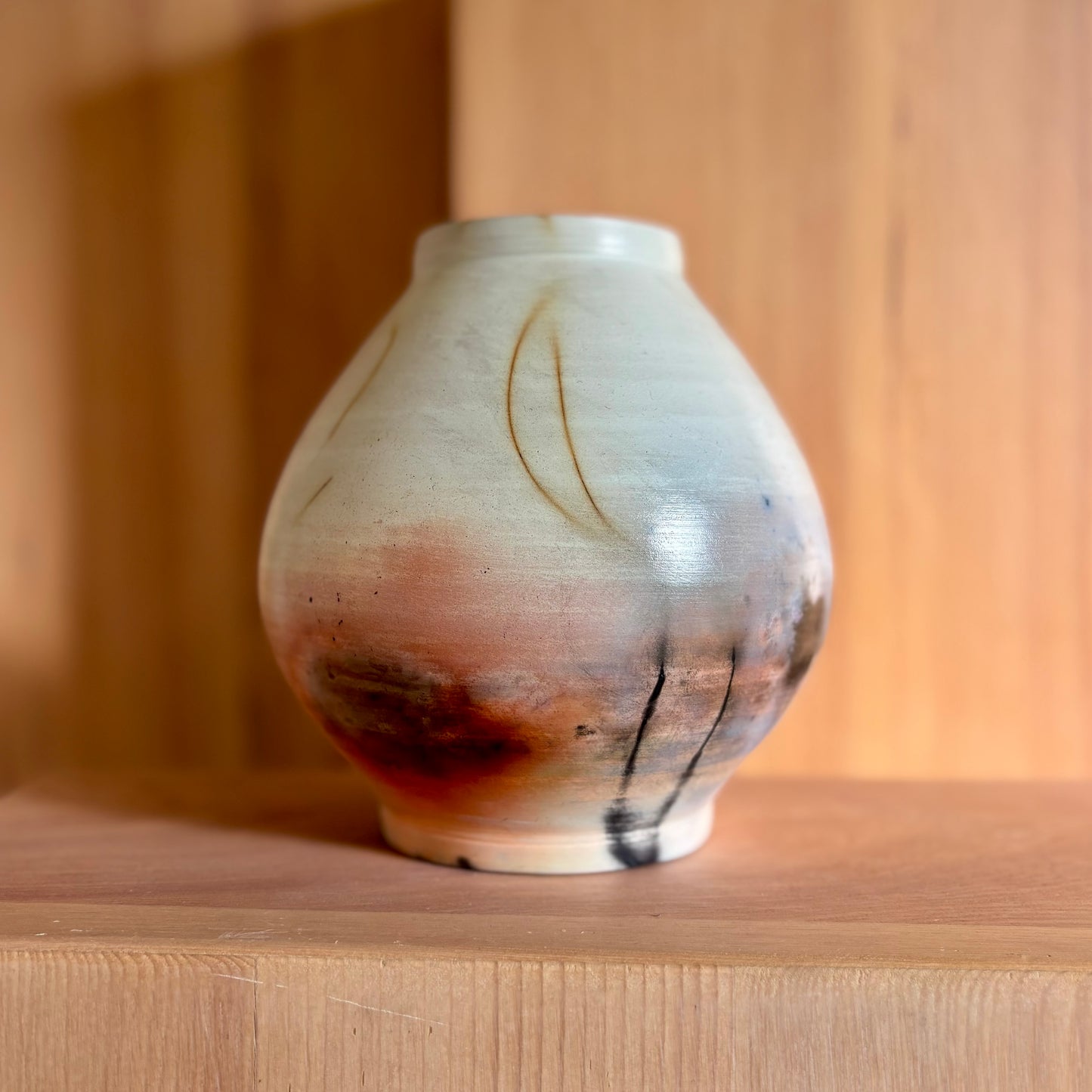 A porcelain moon jar fired in a saagar fire process giving it natural brown black and red hues. Made by Hillit Wahlberg