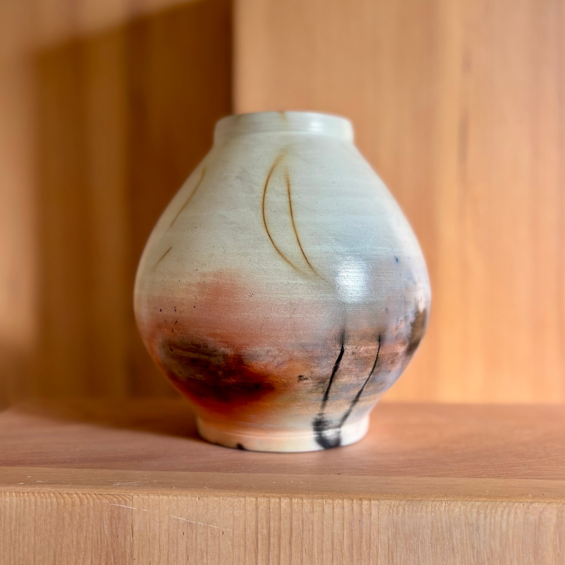 A porcelain moon jar fired in a saagar fire process giving it natural brown black and red hues. Made by Hillit Wahlberg