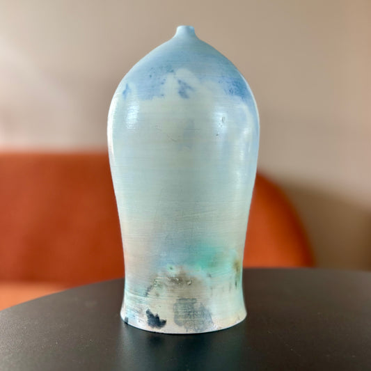 A saggar fired porcelain vase in light shades of blue and green. Made by ceramic artist Hillit Wahlberg