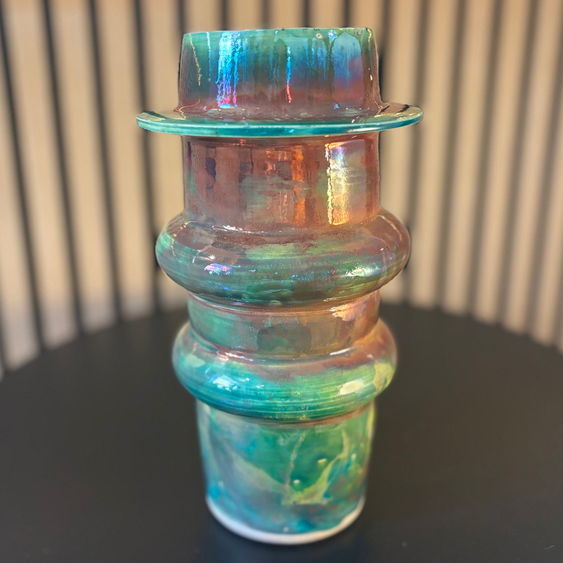 Multicolored porcelain vase on a black surface with a striped background